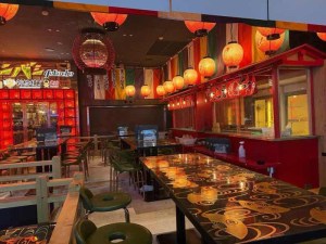 Interior of a lively izakaya in Japan featuring wooden tables, colorful lanterns, and a vibrant atmosphere, ideal for social dining.
