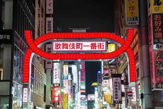 Illuminated entrance sign to a lively street in Japan, surrounded by vibrant neon lights and signage, showcasing the energetic atmosphere of nighttime urban life.