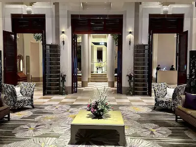 A luxurious hotel lobby featuring elegant seating arrangements, floral carpet design, and decorative elements, creating a welcoming atmosphere.
