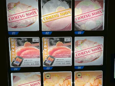 A ticket vending machine display for a ramen shop, featuring food images with 'COMING SOON' stamped across them.