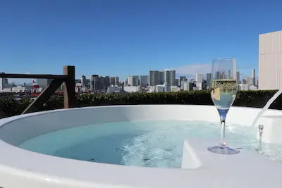 都市の風景を背景にした屋上のジャグジーとシャンパンのグラス