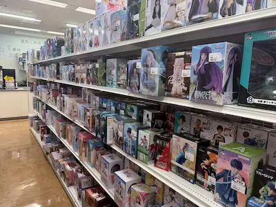 A shelf filled with anime figures and merchandise in a store, showcasing a variety of characters and collectibles.