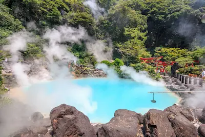 湯煙の上がる青い温泉と緑豊かな自然の風景